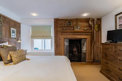 a bedroom with a bed with a fireplace and a television at Lantau Cottage: Historic Elizabethan house very close to the beach in Looe