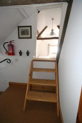 a stair case in a room with a window at Lantau Cottage: Historic Elizabethan house very close to the beach in Looe