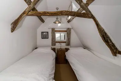 two beds in a attic bedroom with exposed beams at Lantau Cottage: Historic Elizabethan house very close to the beach in Looe