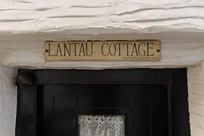 a sign above a black door with a sign above it at Lantau Cottage: Historic Elizabethan house very close to the beach in Looe
