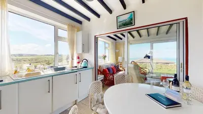 a kitchen with a table and a large window at C16 Treverbyn, Riviere Towans in Hayle