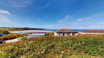 a house on a hill with the ocean in the background at C16 Treverbyn, Riviere Towans in Hayle