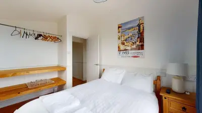 a bedroom with a white bed and a picture on the wall at C25 Weir View, Riviere Towans in Hayle