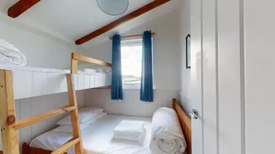 a small room with two bunk beds and a window at C25 Weir View, Riviere Towans in Hayle