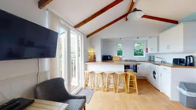 a kitchen with white cabinets and bar stools at C25 Weir View, Riviere Towans in Hayle