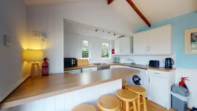 a kitchen with white cabinets and a wooden counter top at C25 Weir View, Riviere Towans in Hayle