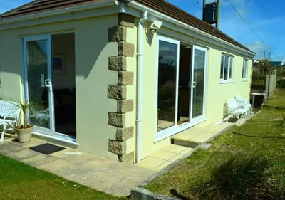 a small house with glass doors and a patio at C27 Eddleston, Riviere Towans in Hayle