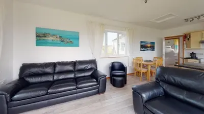 a living room with a leather couch and a table at C27 Eddleston, Riviere Towans in Hayle