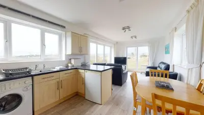 a kitchen and dining room with a table and a washing machine at C27 Eddleston, Riviere Towans in Hayle