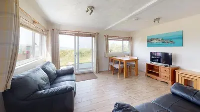 a living room with a couch and a television and a table at C37 Jupiter, Riviere Towans in Hayle