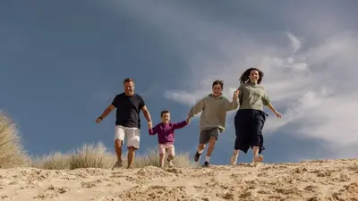 a family running on the sand on a beach at C37 Jupiter, Riviere Towans in Hayle
