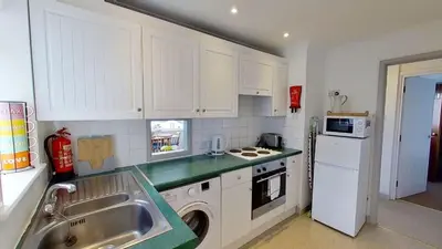a small kitchen with white cabinets and a sink at C41 Windmills, Riviere Towans in Hayle