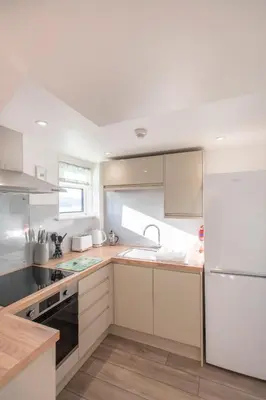 a kitchen with white cabinets and a sink at Sandy Bay Apartment, St Ives Bay, Hayle in Hayle