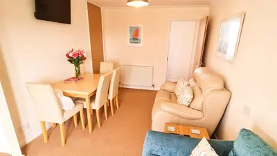 a living room with a couch and a table and chairs at Sandy Bay Apartment, St Ives Bay, Hayle in Hayle