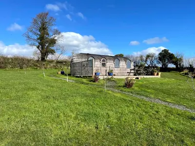 an old barn in a field with a grass yard at The Pasty - Lydcott Glamping in East Looe