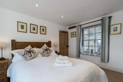 a bedroom with a white bed and a window at Jessamine: Restored fisherman's cottage close to Looe's harbour in Looe