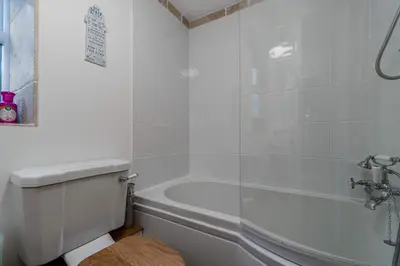 a white bathroom with a tub and a toilet at Jessamine: Restored fisherman's cottage close to Looe's harbour in Looe