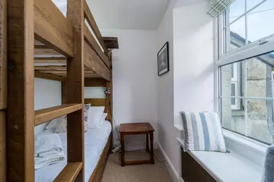 a bedroom with a bunk bed and a window at Jessamine: Restored fisherman's cottage close to Looe's harbour in Looe