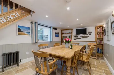 a dining room with a wooden table and chairs at Jessamine: Restored fisherman's cottage close to Looe's harbour in Looe