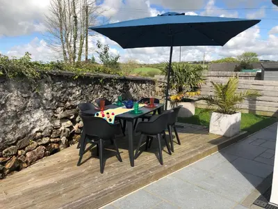 a table and chairs under an umbrella on a deck at UNIQUE CORNISH COTTAGE CONVERSION Central location in Redruth