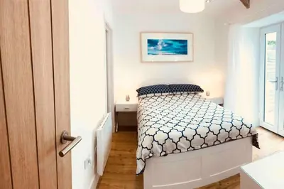a white bedroom with a bed and a sink at UNIQUE CORNISH COTTAGE CONVERSION Central location in Redruth