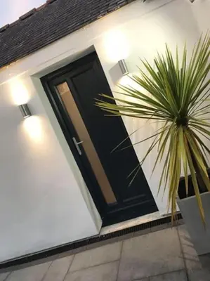 a black door on a white house with a plant at UNIQUE CORNISH COTTAGE CONVERSION Central location in Redruth