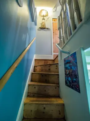 a stairway with a blue wall and a stair case at Birds Nest Cottage Looe in Looe