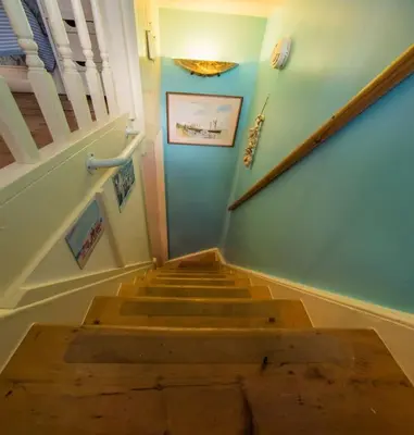a stairway with a wooden table and a stair case at Birds Nest Cottage Looe in Looe