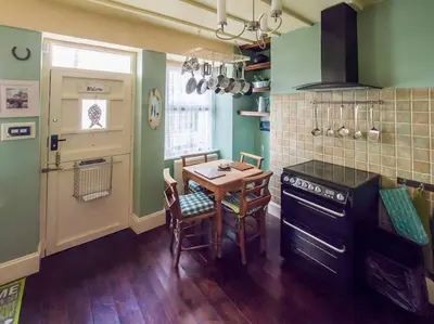 a kitchen with a table and a kitchen with green walls at Birds Nest Cottage Looe in Looe