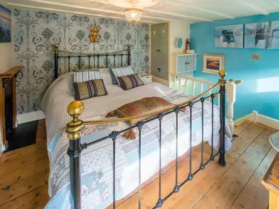 a bedroom with a large bed with blue walls at Birds Nest Cottage Looe in Looe