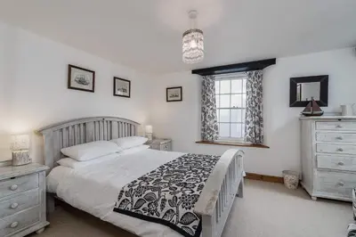 a bedroom with a bed and a window and a dresser at Historic Osborne House very close to the beach in Looe