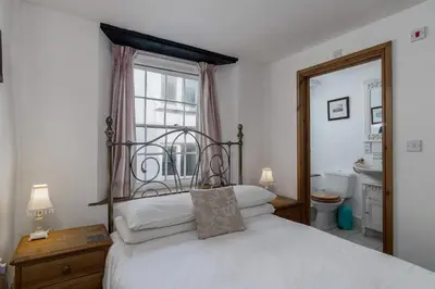 a bedroom with a white bed with a window at Historic Osborne House very close to the beach in Looe