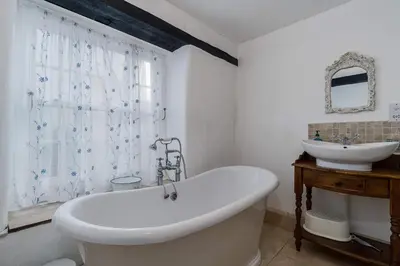 a white bathroom with a tub and a sink at Historic Osborne House very close to the beach in Looe
