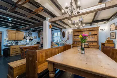 a kitchen with a wooden table with flowers on it at Historic Osborne House very close to the beach in Looe