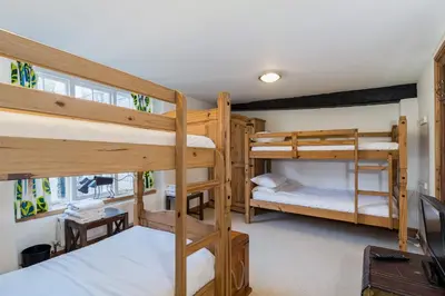 a room with two bunk beds and a television at Historic Osborne House very close to the beach in Looe
