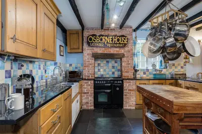 a large kitchen with a brick wall at Historic Osborne House very close to the beach in Looe