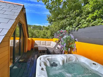 a hot tub on the deck of a house at Chy Glynn. Luxury lodge with hot tub and views. in St. Agnes