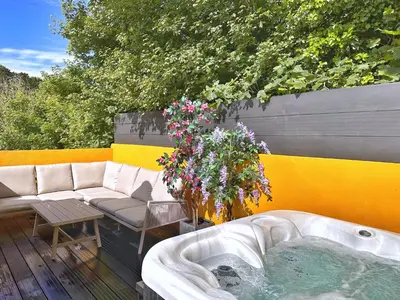 a hot tub sitting on a deck with flowers at Chy Glynn. Luxury lodge with hot tub and views. in St. Agnes