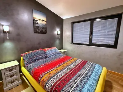 a bedroom with a bed with a colorful comforter and a window at Chy Mena. South facing lodge with hot tub & views. in St. Agnes