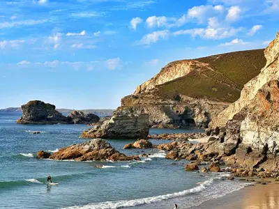 a person riding a wave on a surfboard in the ocean at Chy Mena. South facing lodge with hot tub & views. in St. Agnes