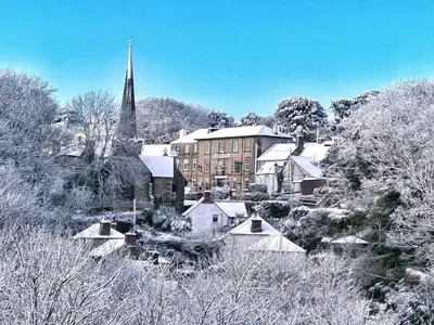 a town covered in snow with a building and a church at Chy Mena. South facing lodge with hot tub & views. in St. Agnes