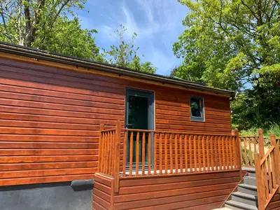 a large wooden cabin with a wooden deck at Chy Cos. South facing lodge with balcony & views. in St. Agnes