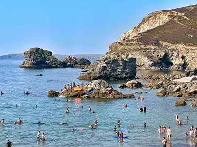 a group of people in the water at a beach at Chy Cos. South facing lodge with balcony & views. in St. Agnes