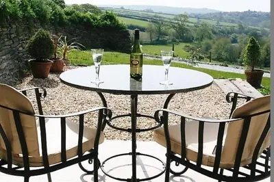 a table with a bottle of wine and two chairs at BADGERS HOLLOW in Fowey