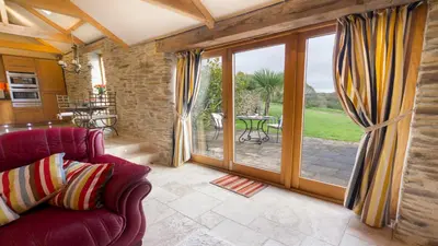 a living room with a red couch and sliding glass doors at BADGERS HOLLOW in Fowey