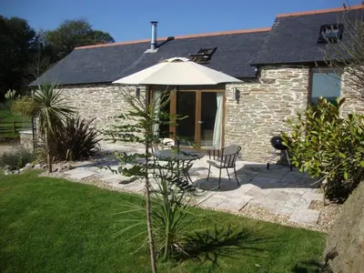 a patio with an umbrella and a table and chairs at BADGERS HOLLOW in Fowey