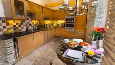 a kitchen with wooden cabinets and a table with food on it at BADGERS HOLLOW in Fowey