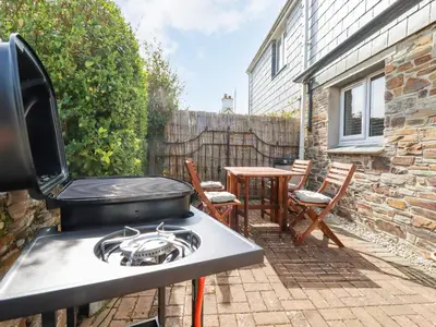 a outdoor patio with a stove and a table at Falcon House in Tintagel