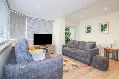 a living room with two couches and a flat screen tv at Falcon House in Tintagel
