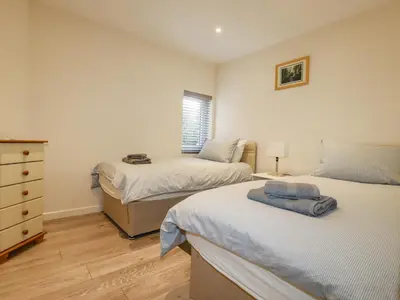 a bedroom with two beds and a dresser and a window at Falcon House in Tintagel